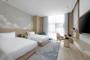 a hotel room with two beds and a flat screen tv at Grand Madison Hotel Wuhan Optical Valley Canglongdao in Liufangling