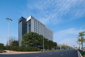 a large building on the side of a road at Grand Madison Hotel Wuhan Optical Valley Canglongdao in Liufangling