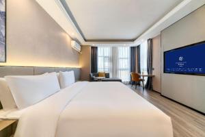 a hotel room with a large bed and a flat screen tv at Starway Hotel Shangrao High-Speed Railway Station in Shangrao