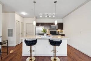 a kitchen with a large island with two bar stools at Houston Med Center Luxury King Suite with Spa Amenities, Pool and Free Parking in Houston