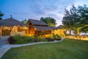 a house with thatched roofs and a grass at Catappa Village Lombok in Sekotong