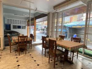 uma sala de jantar com mesa, cadeiras e janelas em โรงแรมไทยโฮเต็ล em Nakhon Si Thammarat