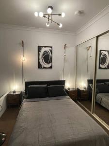 1 dormitorio con 1 cama con 2 lámparas y espejo en Neutral bay studio, en Sídney