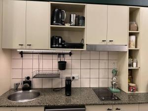 una cocina con armarios blancos y fregadero en Neutral bay studio, en Sídney