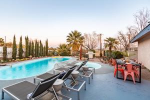 een patio met tafels en stoelen naast een zwembad bij Archie by AvantStay Desert Retreat w Courtyard Edge of Joshua Tree in Yucca Valley