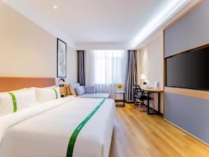 a hotel room with a large bed and a flat screen tv at Green Tree Inn Huhhot Yuquan District South Campus of University of Inner Mongolia in Hohhot