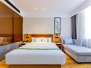 a bedroom with a large white bed and a couch at Green Tree Inn Huhhot Yuquan District South Campus of University of Inner Mongolia in Hohhot