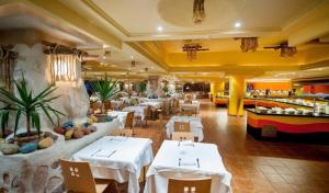 タグエルメスにあるWelcome Meridianaの白いテーブルと椅子が備わるレストラン、ビュッフェ式料理