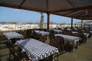 un gruppo di tavoli e sedie con ombrelloni in spiaggia di Welcome Meridiana a Taguermess