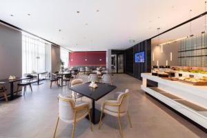 a restaurant with tables and chairs and a counter at Atour Hotel Jinan Tangyan Dongbaqu Enterprise Park in Jinan