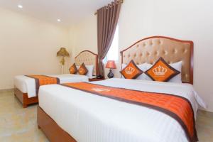 sypialnia z 2 łóżkami w kolorze pomarańczowym i białym w obiekcie Ngọc Long Châu Hotel 