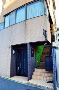 東京にあるHOSTEL LUND I -Oimachi-の黒いドアと階段のあるレンガ造りの建物