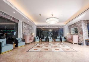 una hall con sedie, tavoli e lampadario a braccio di ALAZMI HOTEL a Al Khān