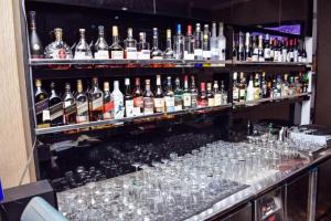 a bar filled with glasses and bottles of alcohol at De Edge Hotel in Rumu-Ome