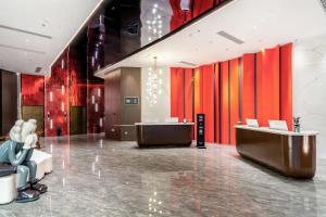 a lobby with red and orange walls and two desks at The Puyan Hotel Hangzhou Jiubao in Hangzhou