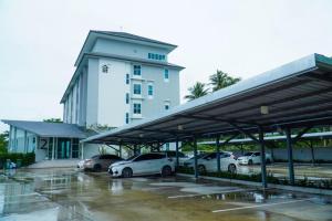 un estacionamiento con autos estacionados frente a un edificio en BM PATTANI APARTMENT en Ban Ru Sa Mi Lae