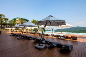 - une terrasse avec des chaises longues et des parasols sur une plage dans l'établissement Sonofelice village Vivaldipark, à Chŏm-ch'on