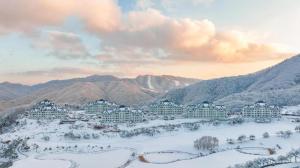 un resort en la nieve con montañas en el fondo en Sonofelice village Vivaldipark, en Chŏm-ch'on