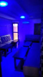 um quarto com luzes e mesas roxas e um sofá em Americana Hotel em Oshodi