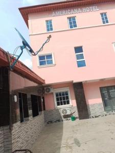 ein rosafarbenes Gebäude mit einem Schild, das amerikanisches Hotel liest in der Unterkunft Americana Hotel in Oshodi