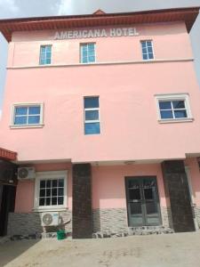 um edifício rosa com o hotel mana americano em Americana Hotel em Oshodi