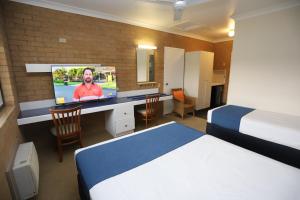 a hotel room with a bed and a tv on a desk at Great Eastern Motor Inn Gympie in Gympie