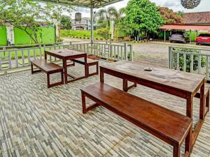 OYO 92024 Green Hotel في جامبي: طاولتان خشبيتان ومقاعد على الفناء