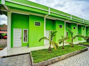 un edificio verde con palmeras delante en OYO 92024 Green Hotel en Jambi