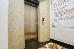 a metal elevator in a room with a wall at TwoSpaces Living at Maximus Inn in Sukarami