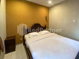 a bedroom with a white bed and a brown wall at Istana Griya 2 Hotel Solo RedPartner in Solo