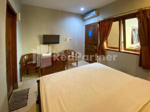 a bedroom with two beds and a table and a television at Istana Griya 2 Hotel Solo RedPartner in Solo