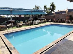 einen großen blauen Pool mit einem Tisch und Stühlen in der Unterkunft Easton Hill Continental Hotel in Enugu