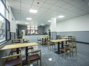 uma cafetaria com mesas e cadeiras de madeira num edifício em Shell Hotel Chuzhou Nanqiao District Wuyi Town Government Town em Wuyi
