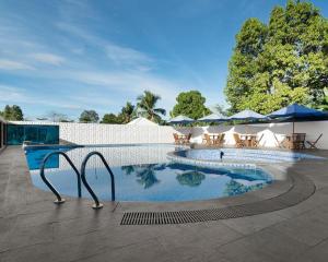 una gran piscina con mesas y sombrillas en Kyriad Hotel M2 Lampung en Kedaton