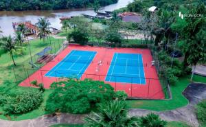 einen Blick über zwei Tennisplätze mit einem Fluss in der Unterkunft IBOM ICON HOTEL AND GOLF RESORT in Mbiakong