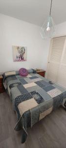een slaapkamer met een bed met een quilt bij Apartamento a pie de playa. in Chiclana de la Frontera