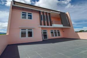una casa rosa con una gran entrada en OYO 92504 Guesthouse Porsea en Banualuhu
