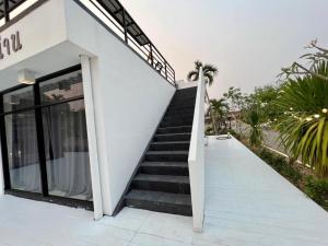 uma escada que leva a um edifício branco com portas de vidro em เฮือนคำเเก้วรีสอร์ท & KK House cafa nan em Ban Don Chai