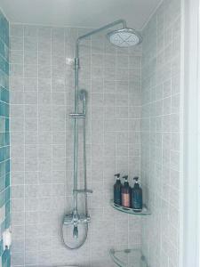 a shower in a tiled bathroom with a sink at THE AVA HOTEL JEJU in Jeju