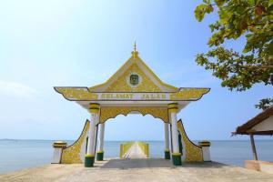 un grande arco con un cartello di fronte all'oceano di Sunset Curly Bay Hotel & Resort a Tanjung Pinang