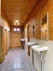 a bathroom with three sinks and two mirrors at Hometravel Mekong Can Tho in Can Tho