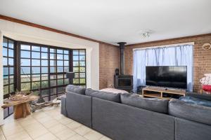 sala de estar con sofá y TV de pantalla plana en Ocean Shores Waterfront 5 Bedroom Home Including SAUNA room, en Kioloa