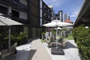 a patio with chairs and umbrellas in front of a building at Coliwoo Keppel Serviced Apartments in Singapore