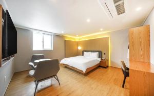 a bedroom with a bed and a tv and chairs at H Avenue Gyeongju in Gyeongju