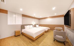 una camera con un grande letto e una TV a schermo piatto di H Avenue Gyeongju a Gyeongju