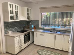a kitchen with white cabinets and a sink and a window at Herbert Cottage in Tumut