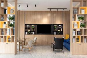 a living room with a tv and a blue couch at Echarm Hotel Zhanjiang Zhanchuan Avenue Wanda Plaza in Zhanjiang