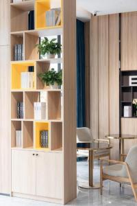 a living room with a book shelf and a table at Echarm Hotel Zhanjiang Zhanchuan Avenue Wanda Plaza in Zhanjiang