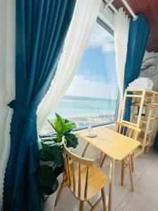 a table and chairs in front of a window with the ocean at Vile Villa Homestay View Biển 01 Đảo Phú Quý in Cu Lao Thu