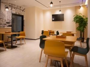 a dining room with tables and chairs and a tv at City Comfort Inn Qianjiang Government in Qianjiang